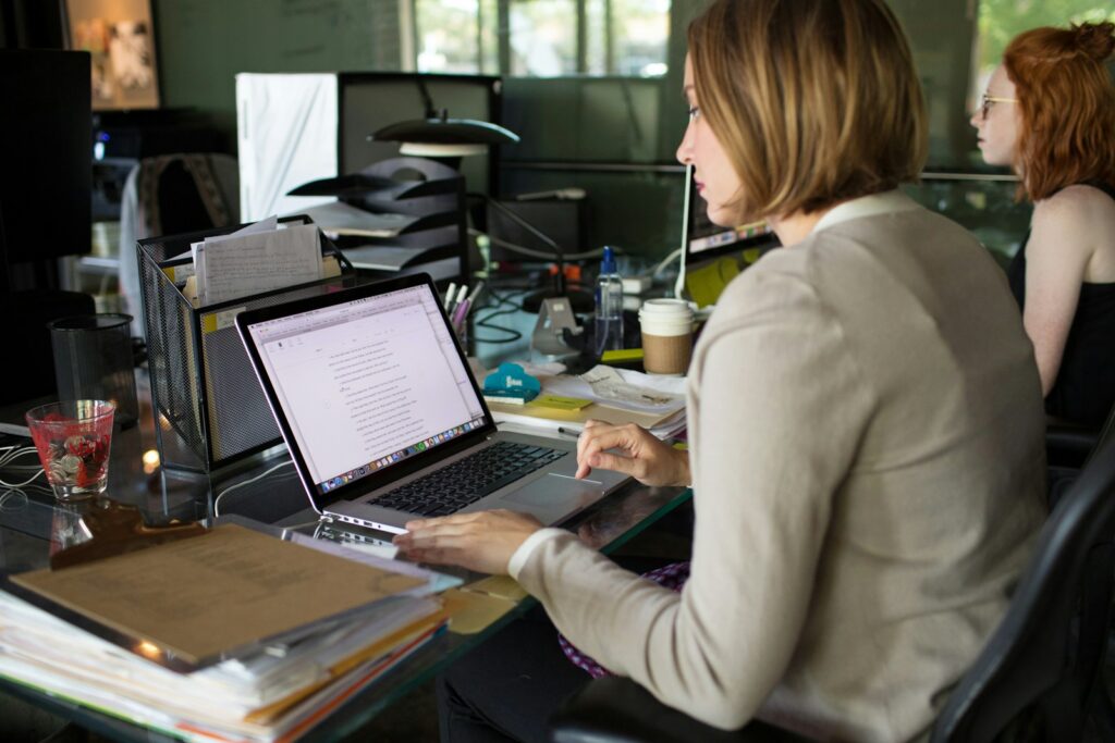 woman in beige blazer using macbook pro